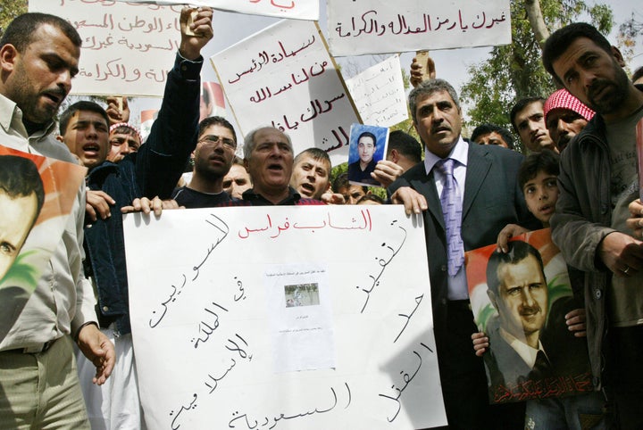 Syrians carry banners and a portrait of Syrian President Bashar al-Assad (R) during a demonstration in Tishrin Park in downto