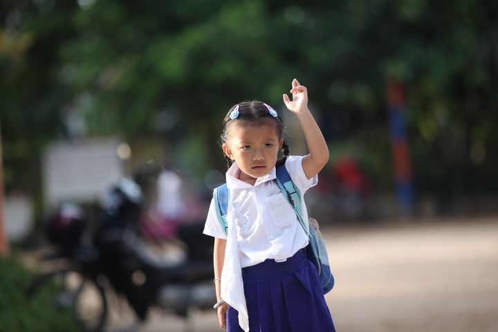 A kindergartner waving her hand to say goodbye to her mother who just dropped her off at school. Location: Spean Chreav Amelio Primary School, Siem Reap. 