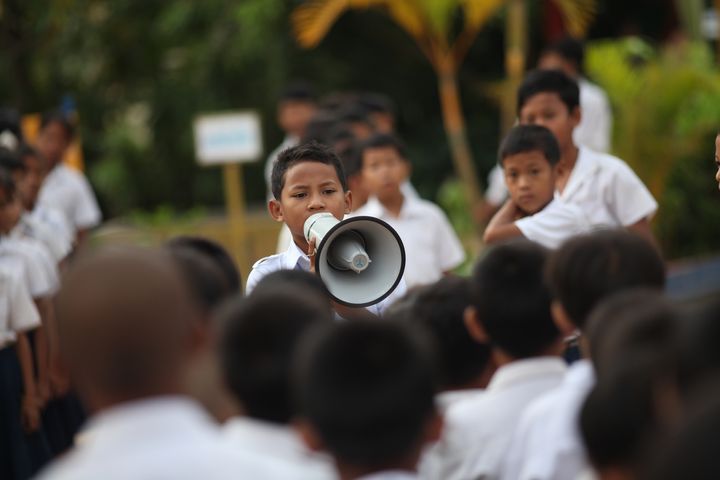 A student leader giving instructions during the flag raising ceremony first thing in the morning before starting school. Location: Spean Chreav Amelio Primary School, Siem Reap. 