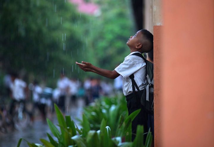 A schoolboy playing in the rain during school recess. Location: Aranh Sakor CFC Primary School, Siem Reap. 
