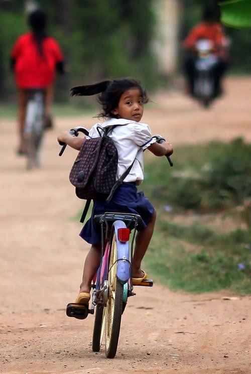 Ponytail flying in the wind as a little girl takes one last look back at school. Location: Koh Dach, Kandal. 