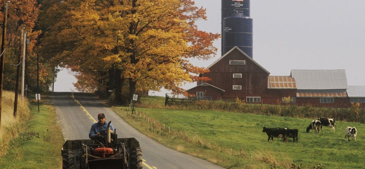 <em>Tractor on farm road with barn and silo in background in autumn, VT</em>