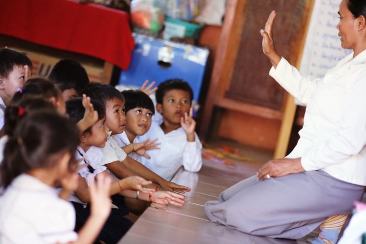 Students raising their hands to answer questions Inside a kindergarten classroom. Location: Kong Much Primary School, Siem Reap. 