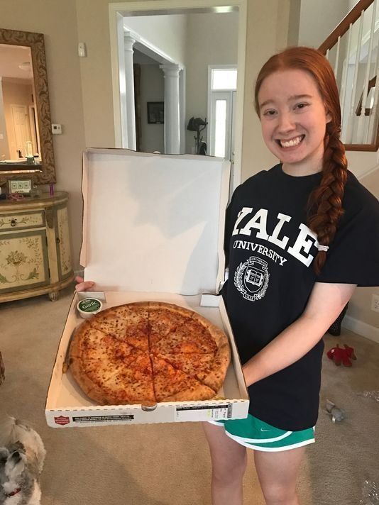 Recent high school graduate Carolina Williams, 18, holds up a Papa Johns pizza after getting accepted into Yale University.