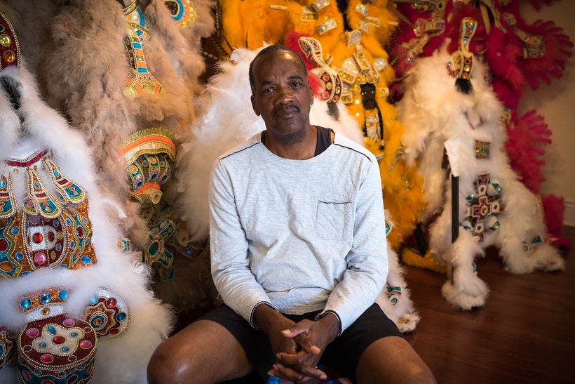 Darryl Montana sits at home in front of several suits he created during previous years.