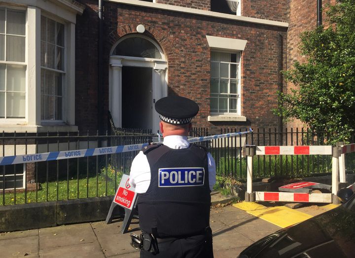 A police officer guards the former Liverpool home of John Lennon where three people were found dead on Tuesday; the deaths have led to a man facing murder charges