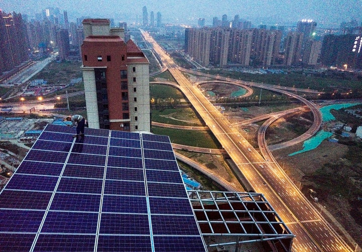 A Chinese worker from Wuhan Guangsheng Photovoltaic Company works on a solar panel project on the roof of a 47 story building in a new development on May 14, 2017 in Wuhan, China.