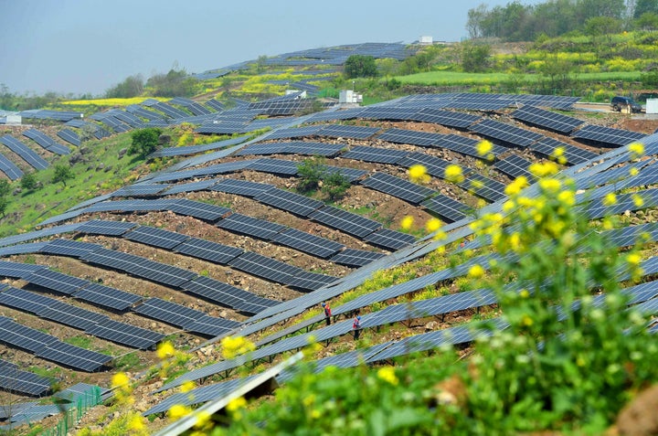 Chinese workers check solar photovoltaic modules on a hillside in a village in Chuzhou, which is in eastern China's Anhui province on April 13, 2017.