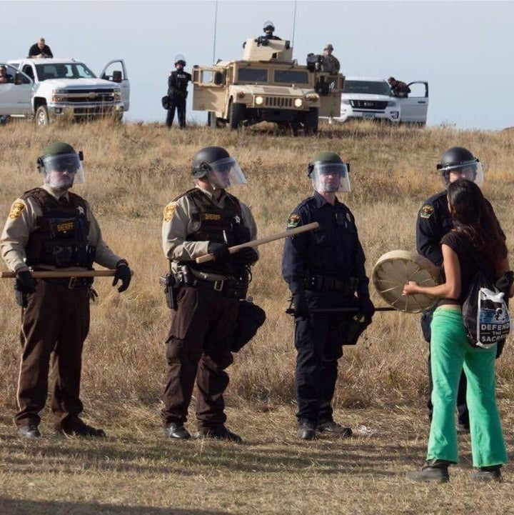Lolly Bee stands near a group of officers in riot gear near the Dakota Access Pipeline construction site in North Dakota