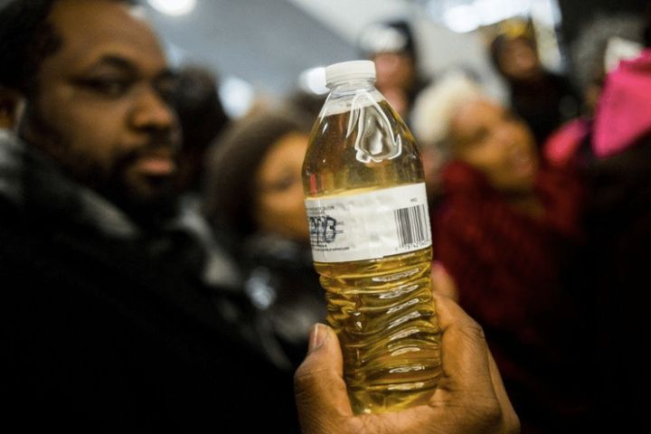<p>A pastor holds up a bottle of Flint water during protests outside of Michigan Gov. Rick Snyder's office in 2015. </p>