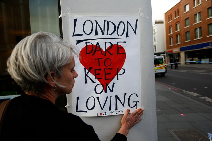 A woman attaches a sign near London Bridge.