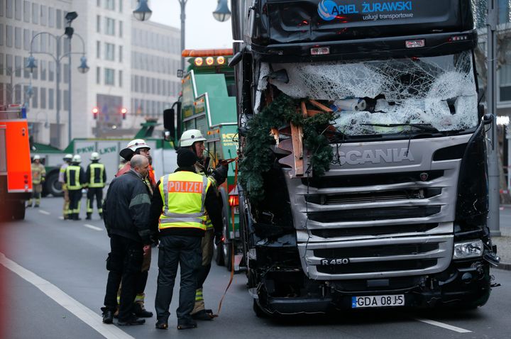 Firefighters stand beside the truck which plowed into a crowded Christmas market in Berlin last December.