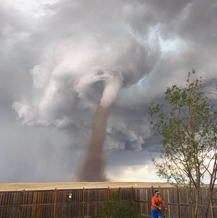 A photo captured a Canadian man appearing to mow his lawn as a tornado loomed in the distance.