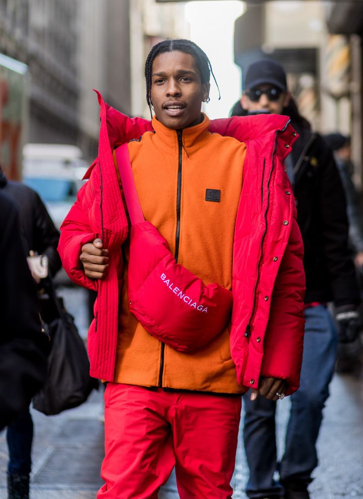 A$AP Rocky wearing a red down feather jacket, Balenciaga bag, orange zip jacket outside Calvin Klein on Feb. 10 in New York City.