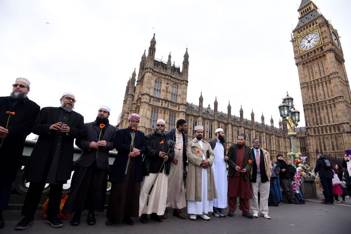 Imams hold flowers as they gather on Westminster Bridge ahead of a vigil to remember the victims of the Westminster terrorist attack