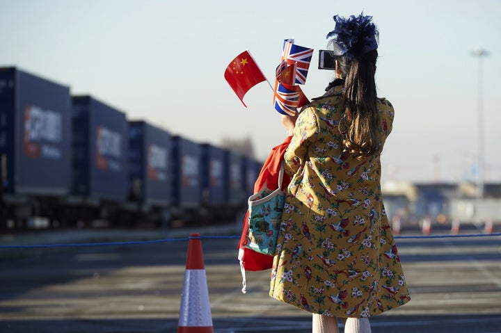 A woman holds Chinese and British flags as she watches the first freight train to travel from China arrive in London's Barking depot, a journey of 18 days and 12,000 kilometers. Jan. 18.