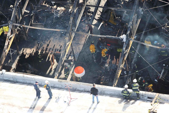 Recovery teams examine the charred remains of the two-story converted warehouse that caught fire killing dozens in Oakland, D