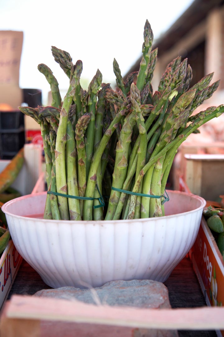 A bunch of fresh asparagus stored in a bowl of water. 