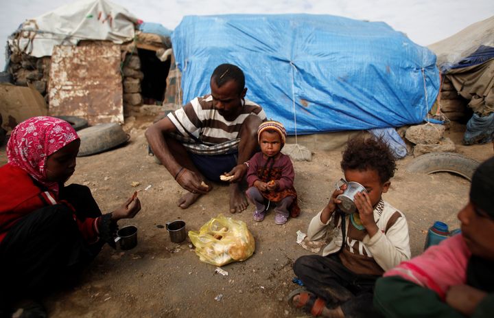 A family eat breakfast outside their hut at a camp for people displaced by the war near Sanaa, Yemen September 26, 2016.