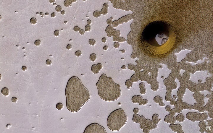 This strange, nearly perfectly circular feature in a “Swiss Cheese” area of Mars has scientists wondering if it was formed from something that fell from the sky, or if it resulted from a ground collapse.