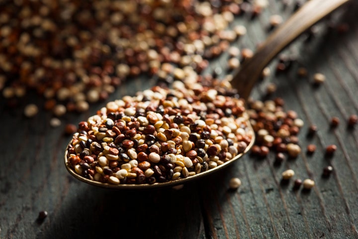 A close up of dried quinoa, measured out on a spoon.