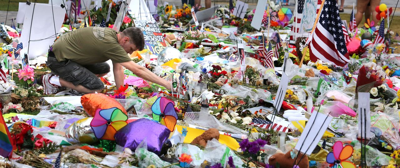 A visitor to the makeshift memorial for the victims of the Pulse massacre relights a candle after an afternoon rain shower at the Dr. Phillips Center for the Performing Arts in downtown Orlando, Fla., on Saturday, June 18, 2016.