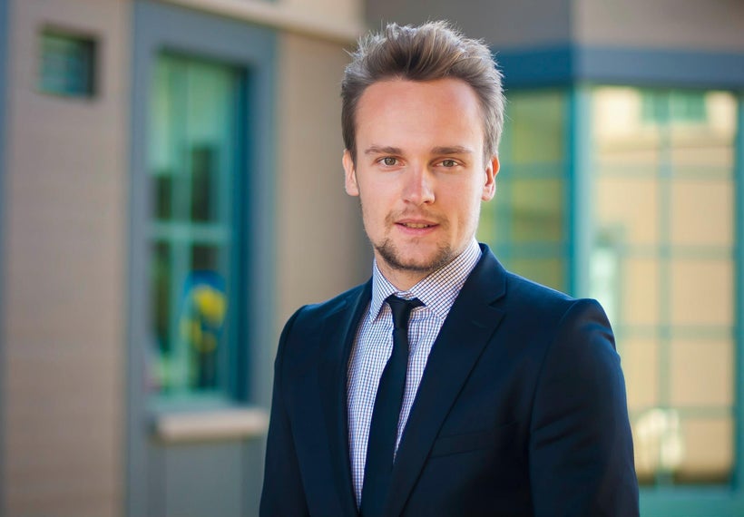 Kirill stands in front of a building at the Haas School of Business where he graduated in 2014.