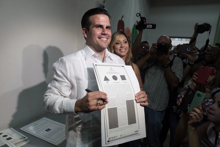 Puerto Rico Governor Ricardo Rossello (C) shows his ballot paper next to his wife Beatriz Rossello as Puerto Ricans head to t