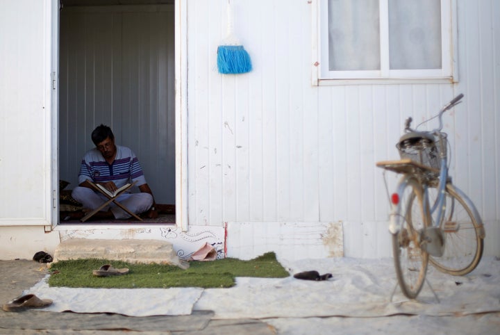 A Syrian refugee man reads the Koran inside his home at the Al-Zaatari refugee camp on June 1.