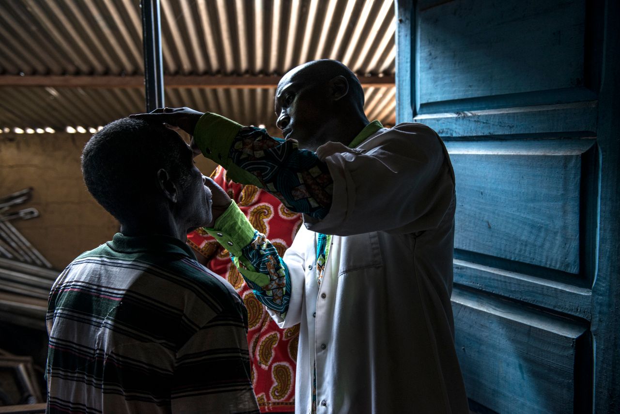 A Congolese doctor checks a patient's eyes.