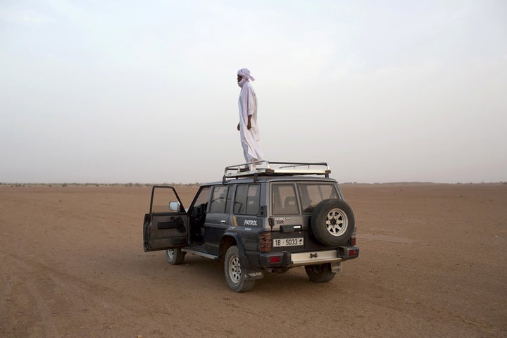  A human smuggler looks out for cars driven by his colleagues coming from Libya from the Niger in March 2014. 