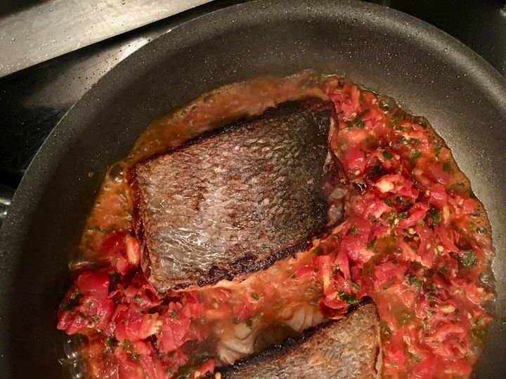 The tomatoes and mint are added to the skillet; the fish finishes cooking in this mixture