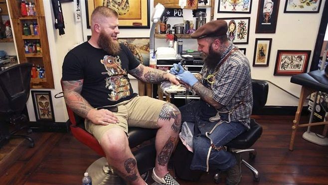 A man gets a U.S. flag tattooed on his hand at Jack Brown’s Tattoo Revival in Fredericksburg, Virginia. As tattoos, piercings and other body art becomes more popular, state regulators are racing to keep up.