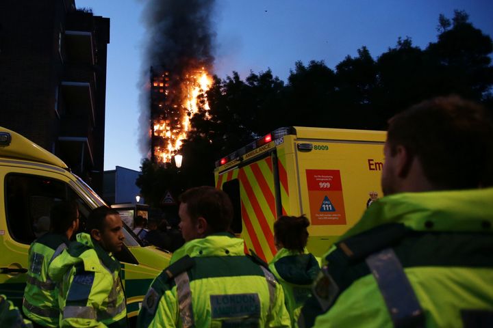Members of the emergency services watch as Grenfell Tower is engulfed by fire on June 14, 2017 in west London.