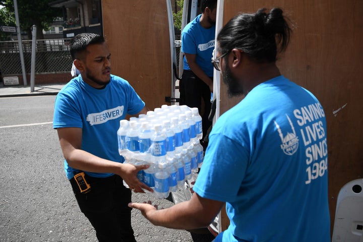 Islamic Relief charity workers arrive with bottled water near the 24 storey residential Grenfell Tower block in Latimer Road, West London on June 14, 2017 in London, England.