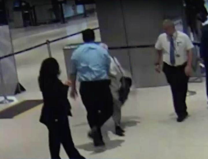 Surveillance video shows passenger Ronald Tigner being shoved to the floor by a United Airlines employee in a blue shirt.