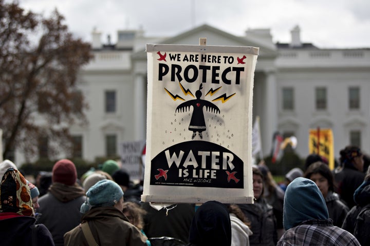 A demonstrator holds a 'Water Is Life' sign in front of the White House during a protest against the Dakota Access Pipeline i