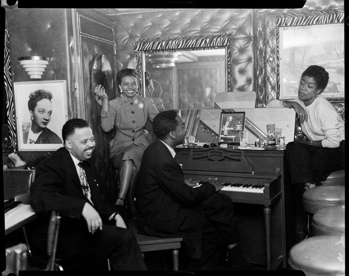 Frank Bolden, unknown woman, man playing piano, and Sarah Vaughan on right, in club with upholstered walls, zebra striped trim, and portrait of Ann Baker, c. 1950