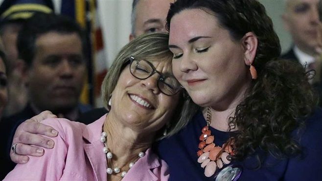A Massachusetts woman whose daughter died of a heroin overdose is hugged by her other daughter at a ceremony marking Republican Gov. Charlie Baker’s signing of a package of opioid addiction measures. Baker has proposed expanding the use of civil commitment for people addicted to opioids.