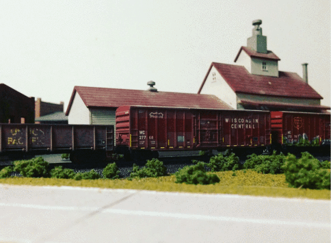 <p><em>One of the very few photos we have of one of Dad’s many different scaled model train set layouts; he painted or placed every decal with precision.</em></p>