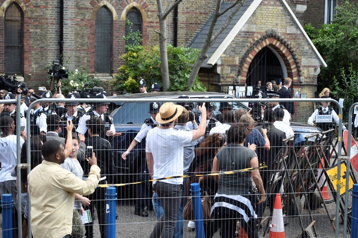 Police officers protect the entourage carrying Theresa May