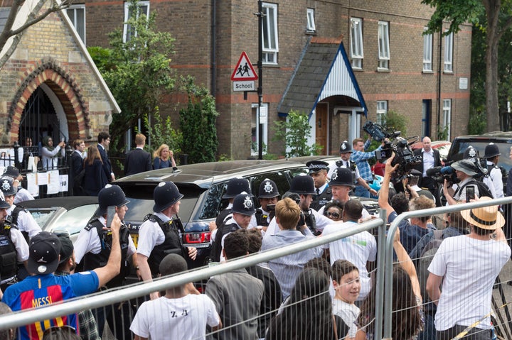 Police protect the PM's entourage as angry resident harangue her after meeting survivors of the fire