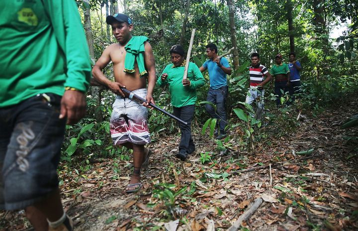 A member of the Ka'apor indigenous tribe carries a rifle confiscated from a man suspected of setting an illegal fire for logging on their protected land on Nov. 23, 2014, in the Ka'apor Indigenous Reserve in Maranhao State, Brazil.