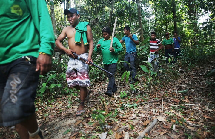 A member of the Ka'apor indigenous tribe carries a rifle confiscated from a man suspected of setting an illegal fire for logg