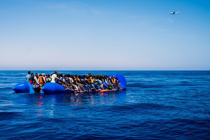 Migrants and refugees wait to board a Proactiva Open Arms' rescue vessel after being rescued from a wooden boat sailing out o