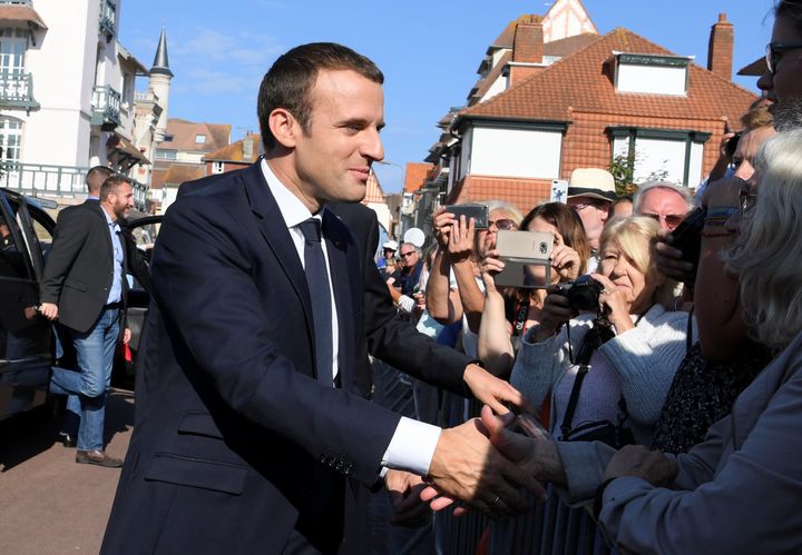 French President Emmanuel Macron (L) shakes hands with people outside the city hall where he votes in the second round of parliamentary elections in Le Touquet, France, June 18, 2017. 