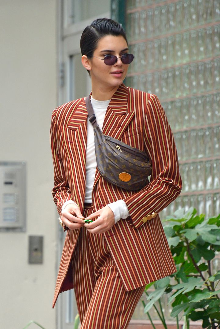 Kendall Jenner wears a modern brown striped suit with white sneakers and her fanny pack while out window shopping at Phillip Lim in NYC. 