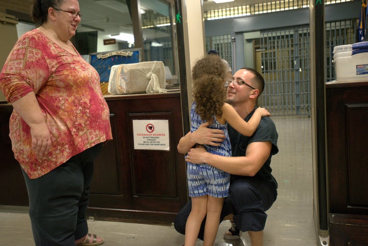 Corey Ladd hugs his daughter, Charlee, while his mother, Lisa, watches.