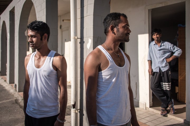 Three Bangladeshi migrants stand outside Hotel Circe, an abandoned building turned into a migrant reception centre, currently