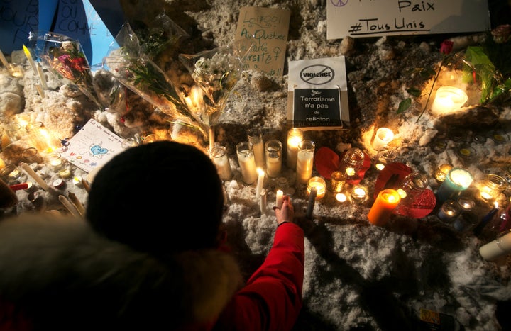 A woman places a candle at a memorial site in Quebec following the mass shooting